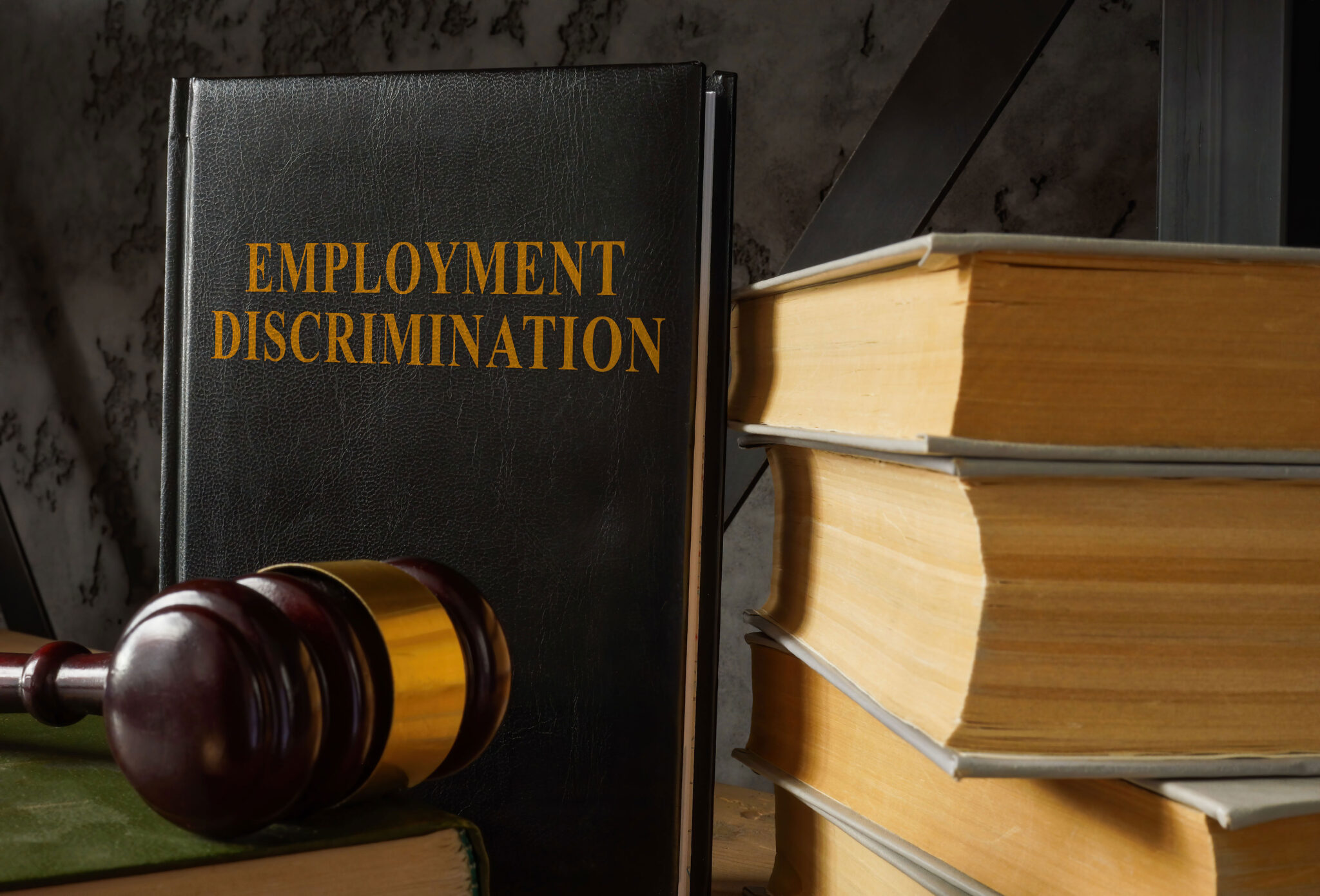 Book titled employment discrimination beside a judge’s gavel and law books.